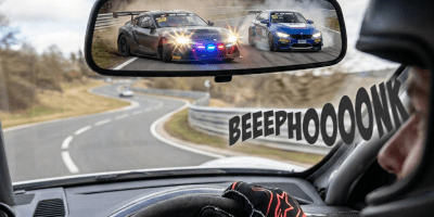 Race car visible in rearview mirror on a winding racetrack