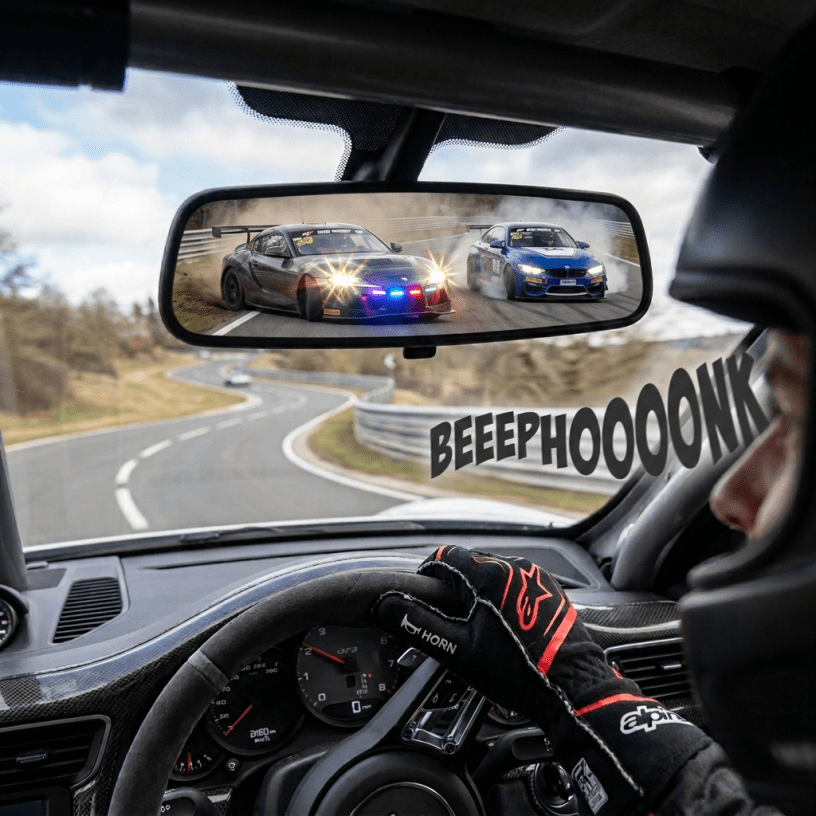 Race car visible in rearview mirror on a winding racetrack